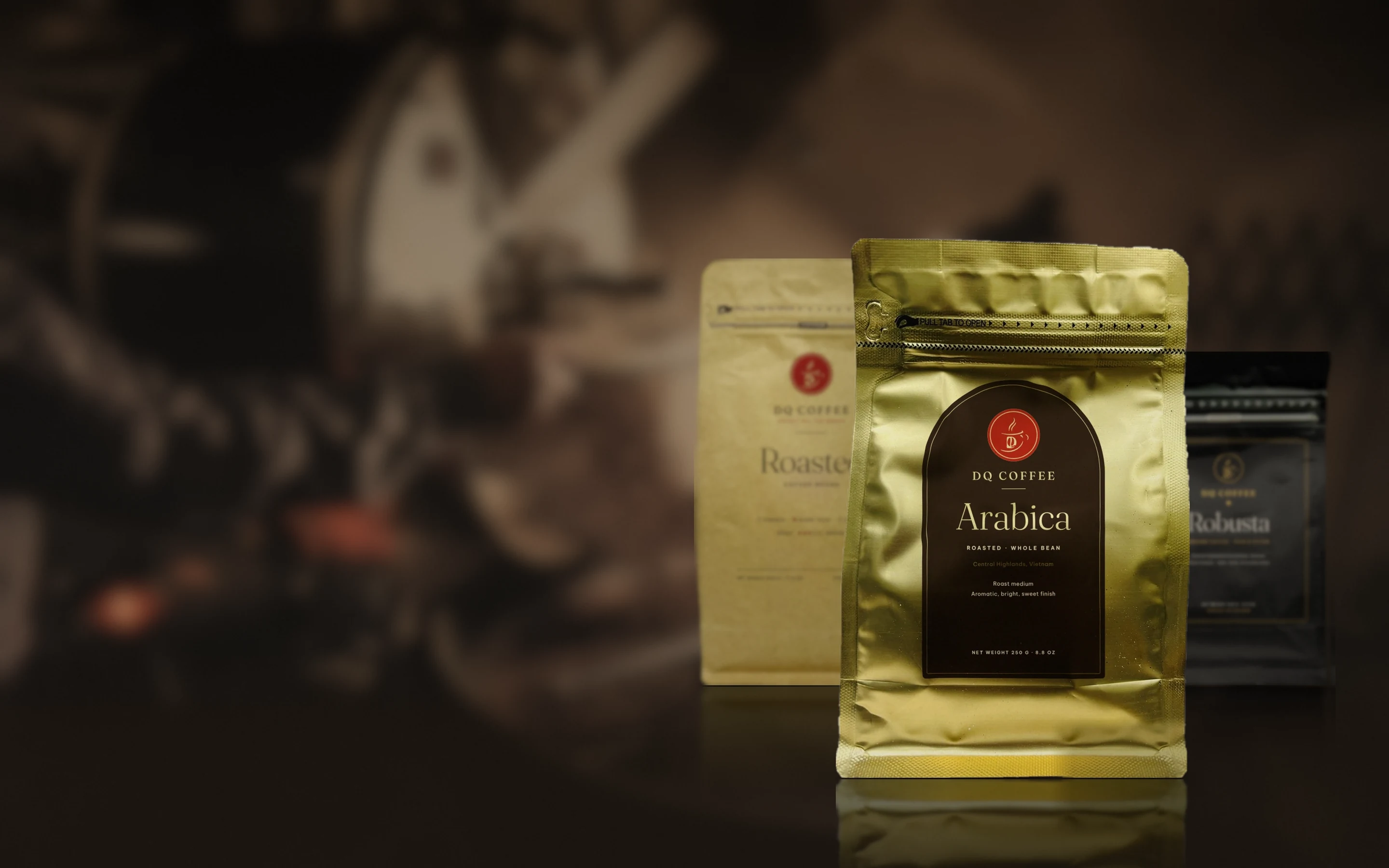 DQ Coffee roasted coffee bags, Arabica, Robusta and a 70/30 blend, on a dark floor, with a small coffee roastery far behind